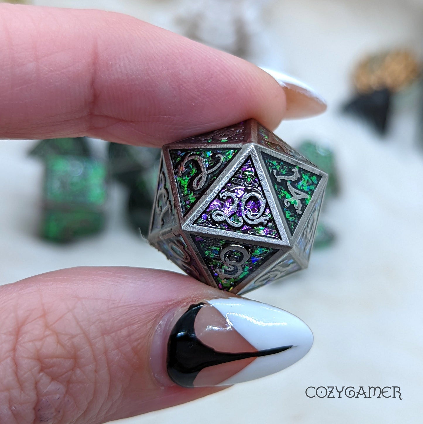 Hand holding a Nickel Cloud Dragon DnD dice with purple and green glitter, nickel borders, and dragon-themed font for tabletop games.
