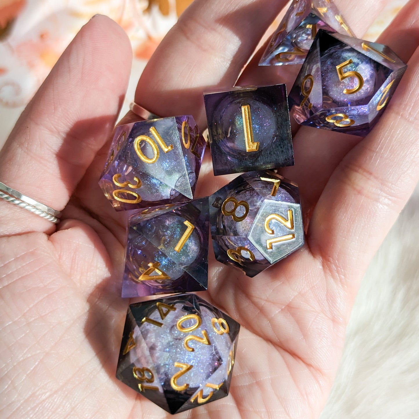 Hand holding Night Castle purple and black liquid core polyhedral resin dice set with shimmer for DnD and tabletop RPGs.