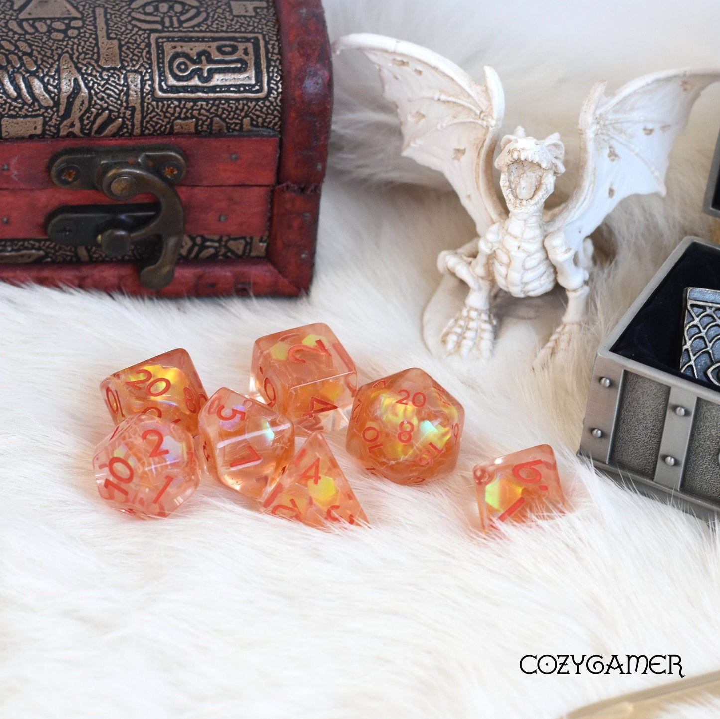 Orange Glint Dice Set with iridescent glitter, perfect for Dungeons and Dragons, displayed on white fur with decorative items.