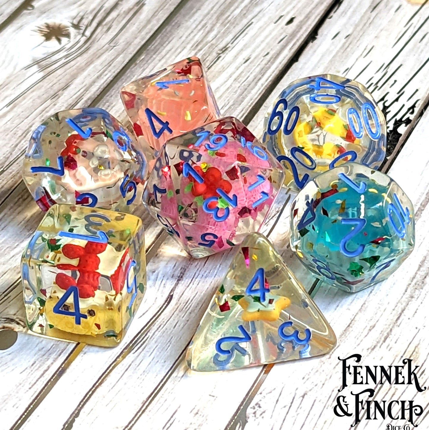 Pastry Dice Set with colorful miniature pastries inside, designed for tabletop RPGs, shown on wooden surface.