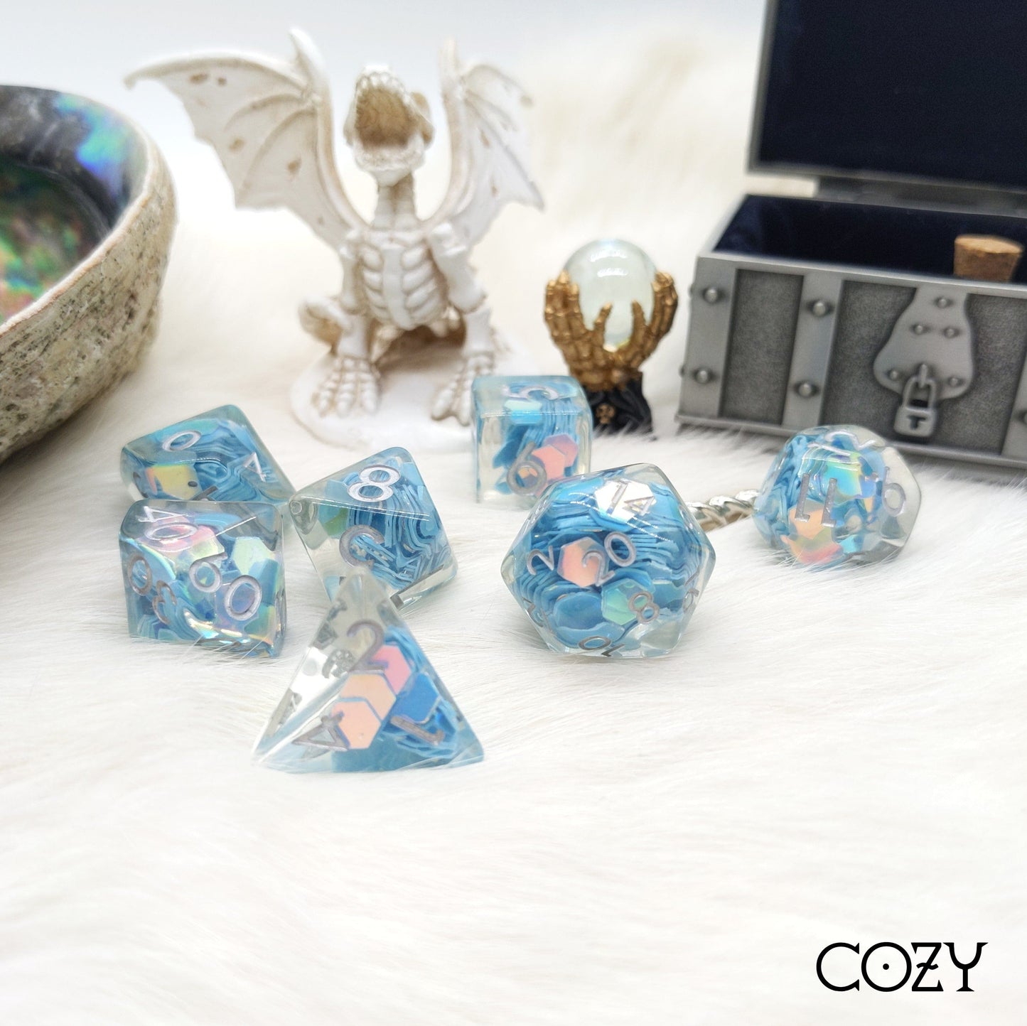 Periwinkle Glint Dice Set with hexagonal blue rainbow glitter, perfect for Dungeons and Dragons, displayed with fantasy figurines.