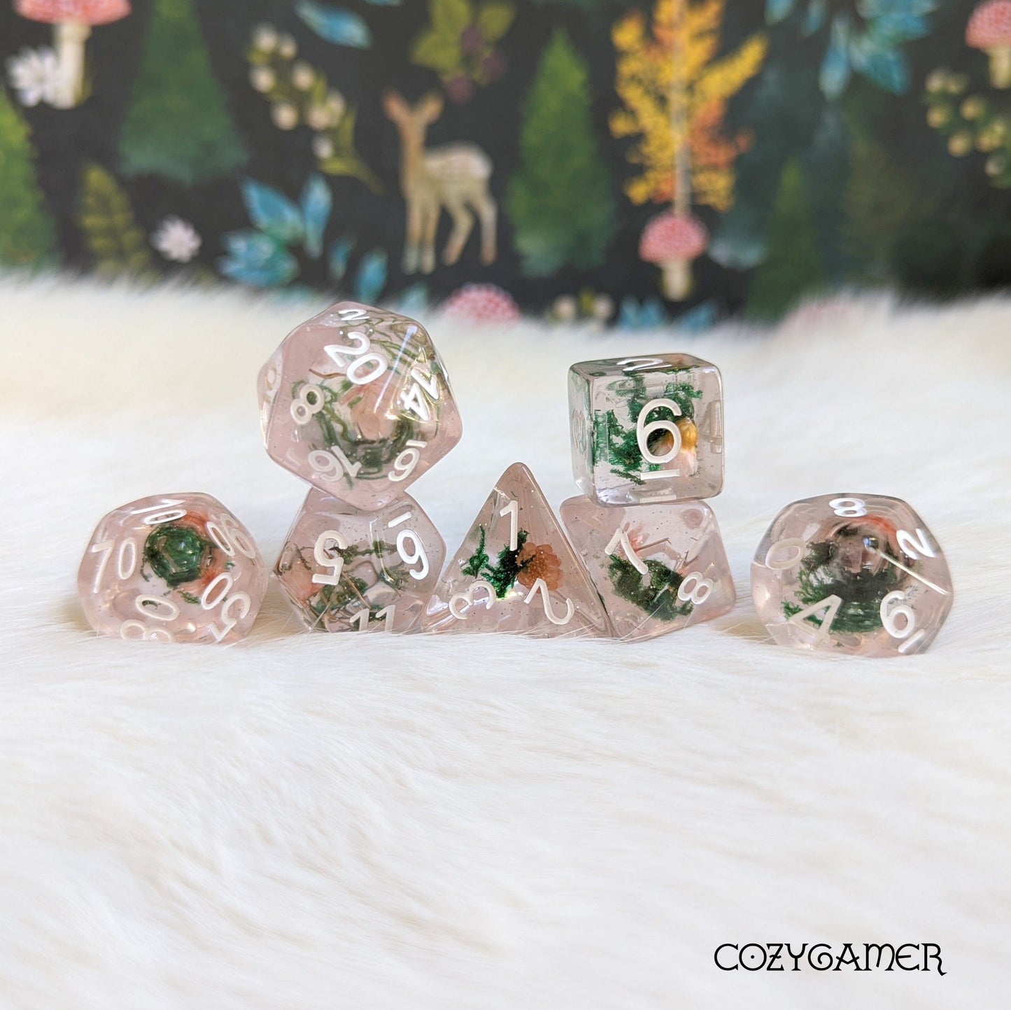 Pink flower and moss dice set with real dried plants in clear resin, 7 polyhedral pieces for DnD, on a soft background.