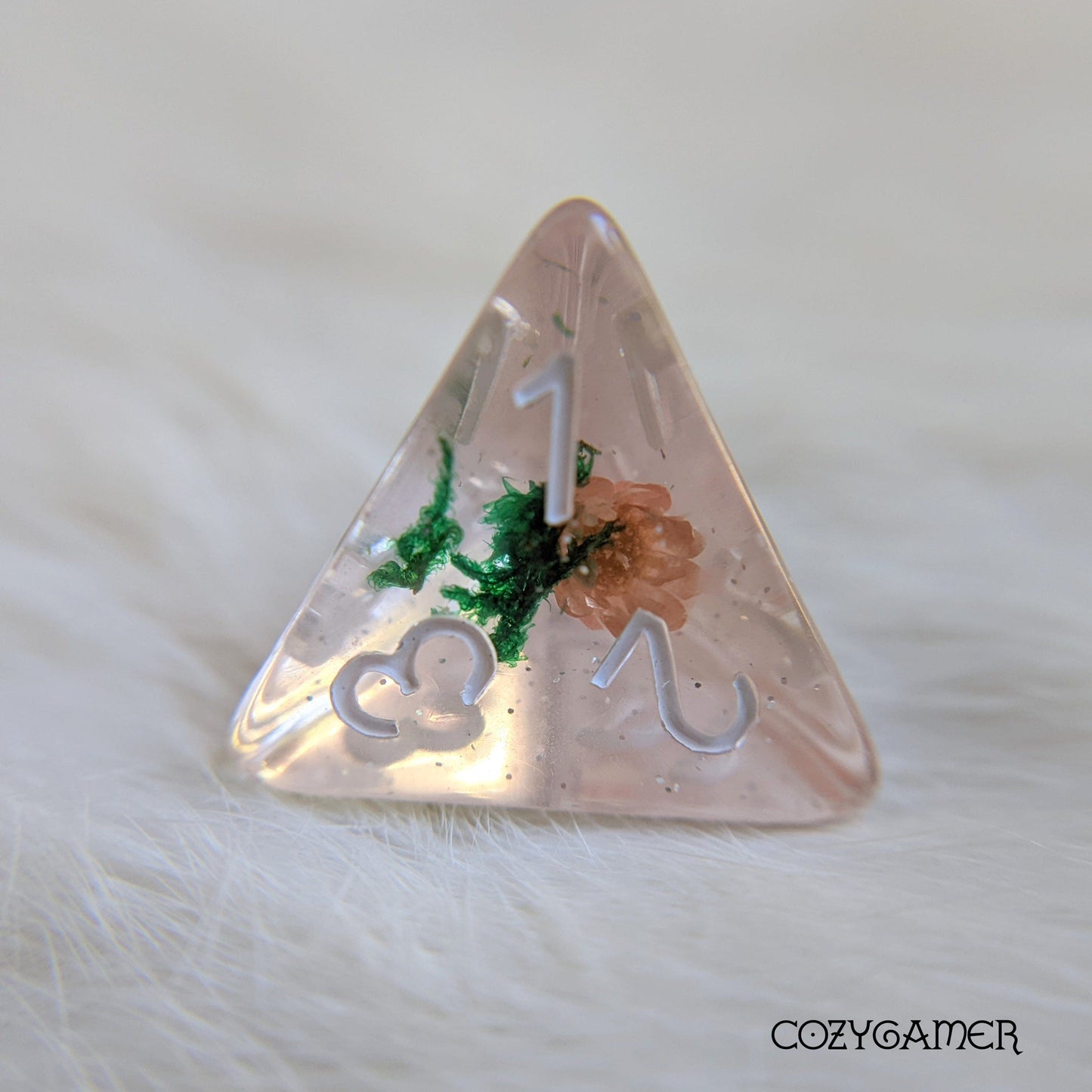 Pink flower and moss D4 dice in clear resin with glitter for tabletop RPGs like Dungeons and Dragons. CozyGamer TTRPG accessory.