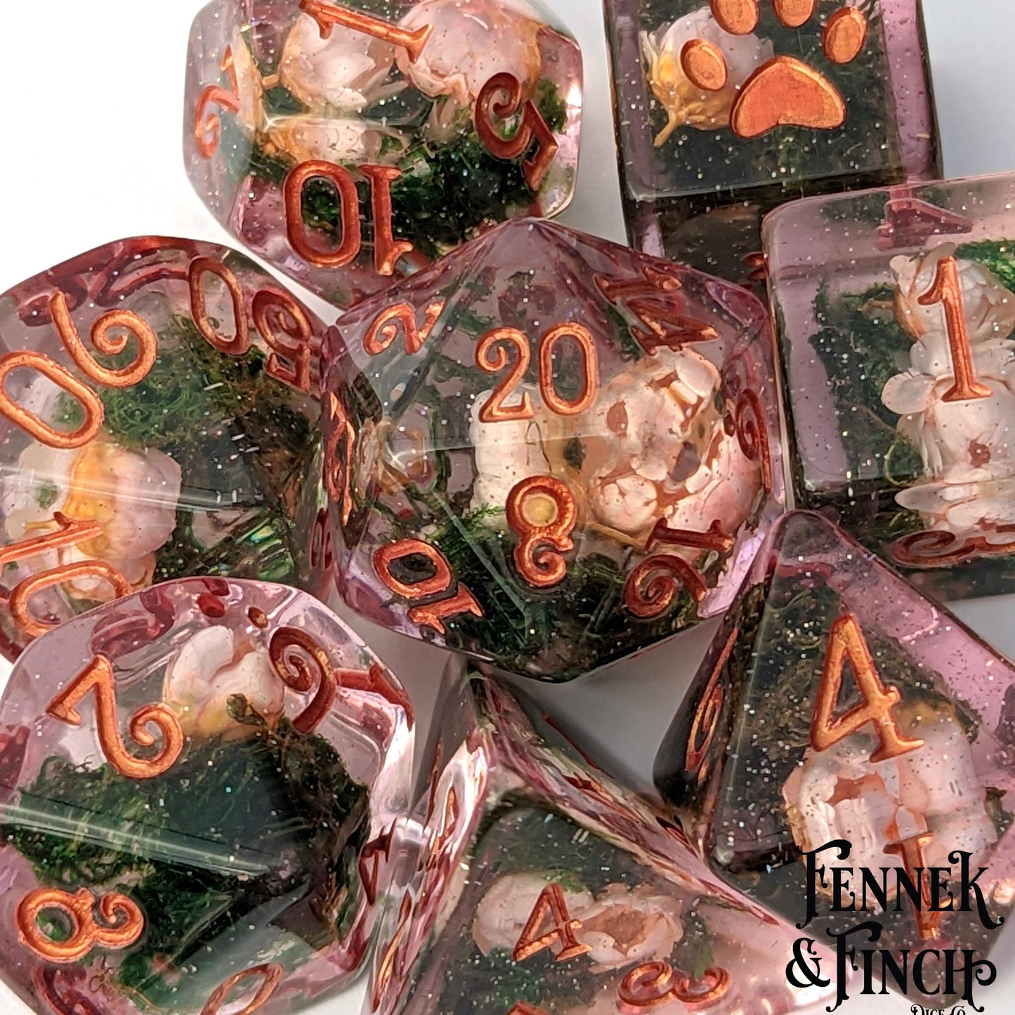 Pink flowers and moss DnD dice set with glittering resin, featuring numbers in shimmering rose gold tones.