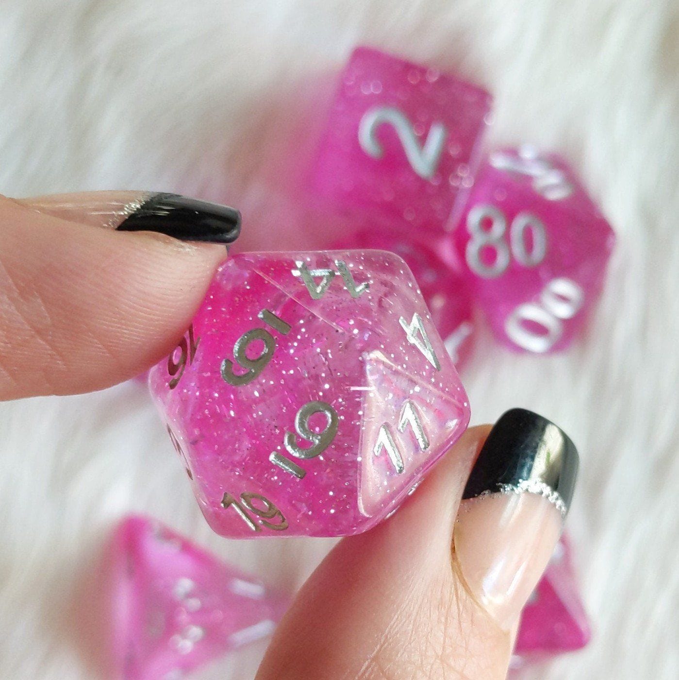 Clear pink glitter polyhedral dice set with silver numbers for tabletop games, showcasing a D20 dice. Perfect for Dungeons & Dragons.