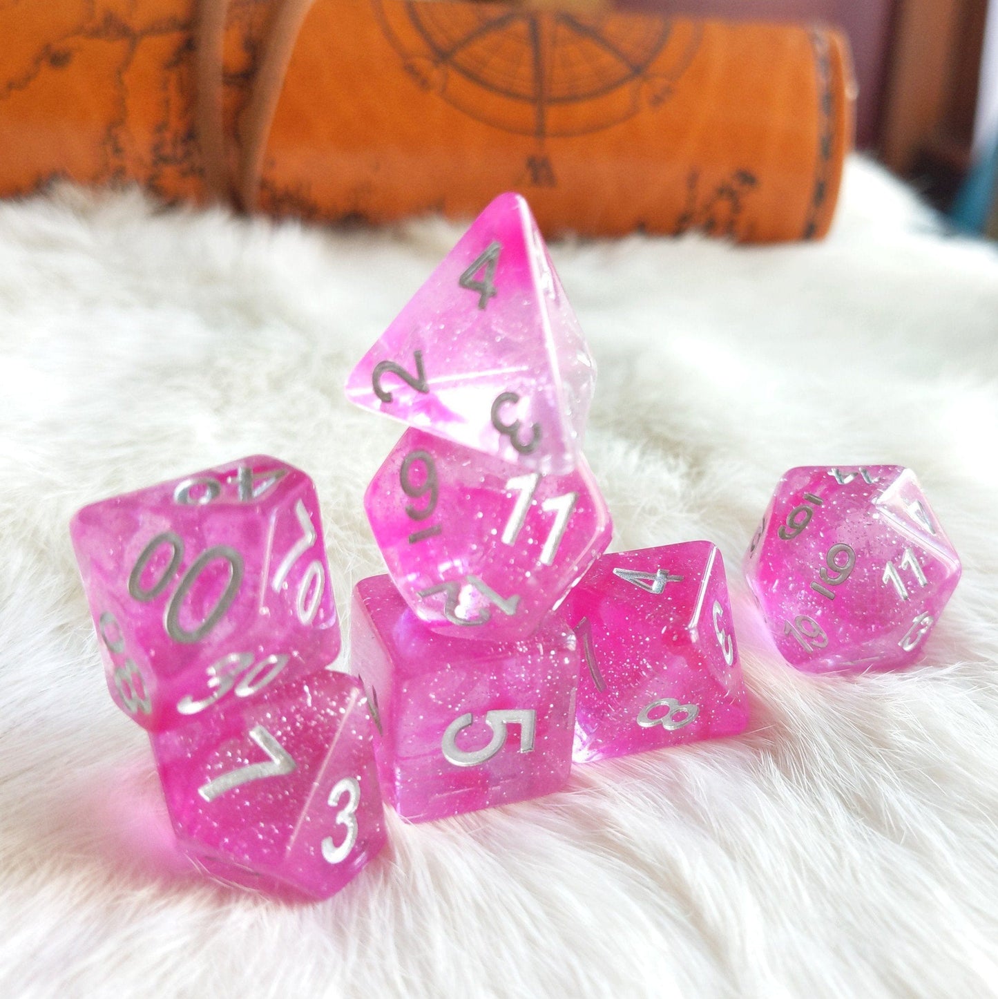 Clear pink glitter pompadour dice set with silver numbers for tabletop role-playing games like Dungeons and Dragons.