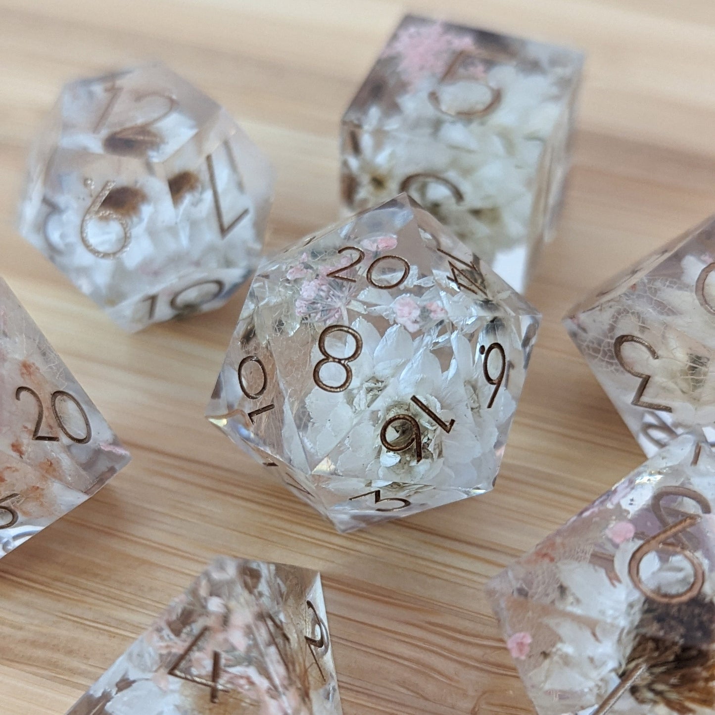 Prairie Flowers DnD Dice Set with daisies, Queen Anne's Lace, and Hydrangea leaves in clear resin on a wooden surface.