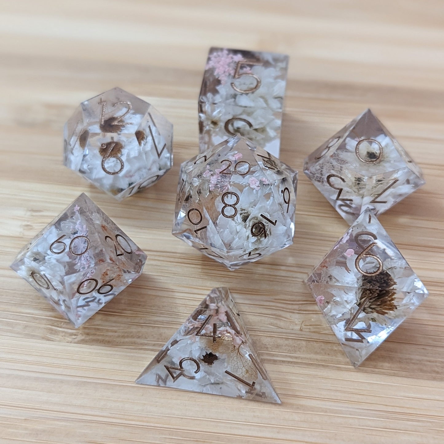 Prairie Flowers sharp edge DnD dice set with embedded white daisies, pink lace, and brown hydrangea on wooden surface.