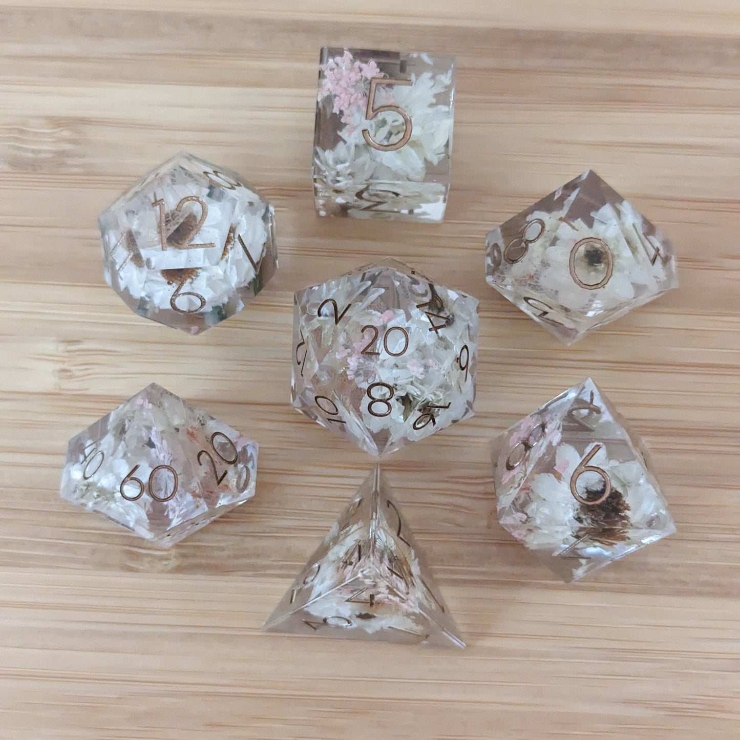 Prairie Flowers DnD Dice Set featuring white daisies and pink flowers in clear resin on a wooden surface.