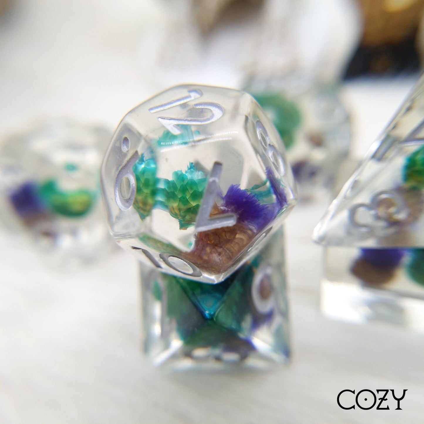 Polyhedral dice set with real dried purple and blue flowers in clear resin, perfect for Dungeons and Dragons and TTRPGs.