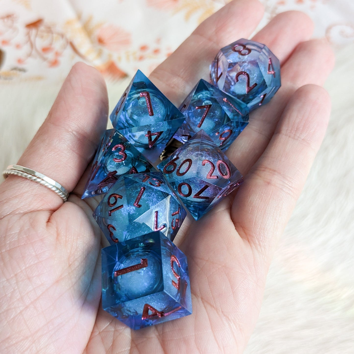 Purple and blue liquid core resin DnD dice set with micro shimmer, displayed on a hand, ideal for tabletop role-playing games.