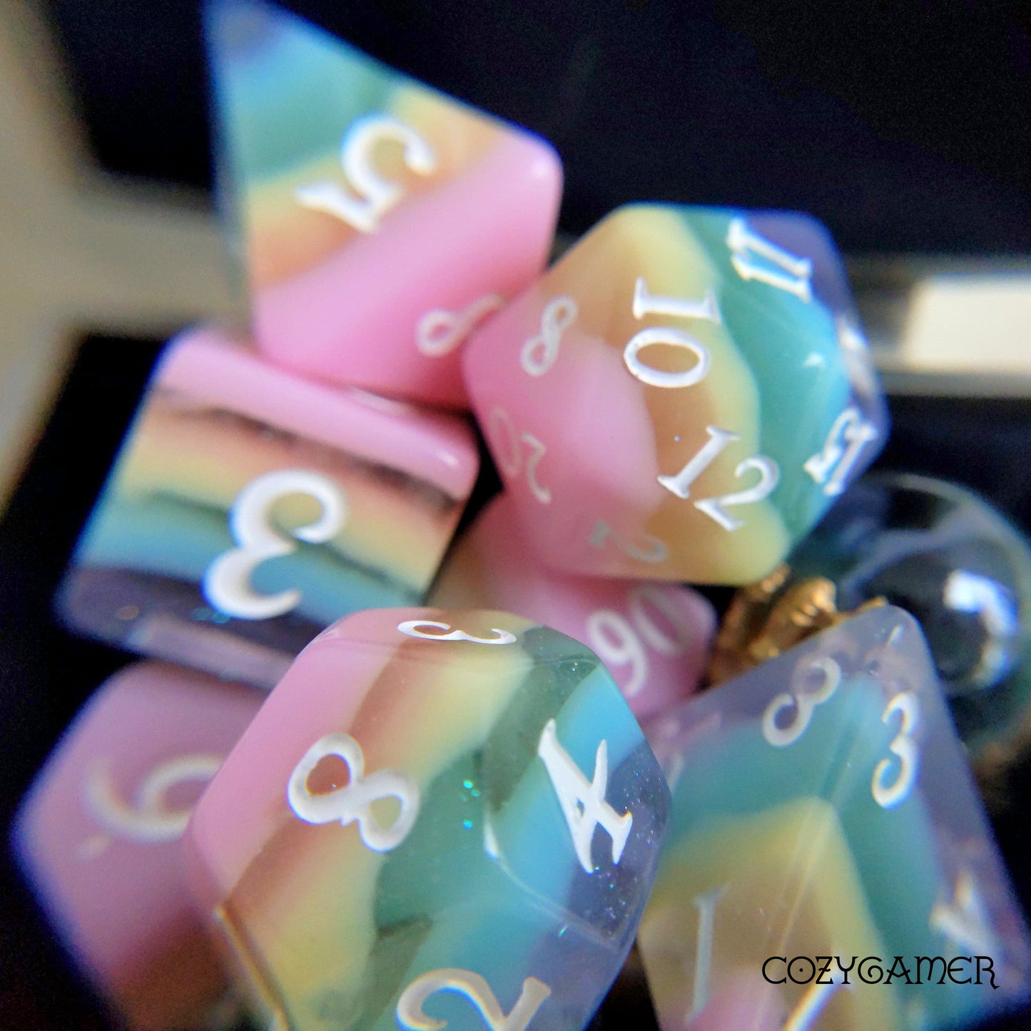 Pastel rainbow stripe DnD dice set with opaque and clear glittering layers, featuring a standard 7 piece set and extended 11 piece option.