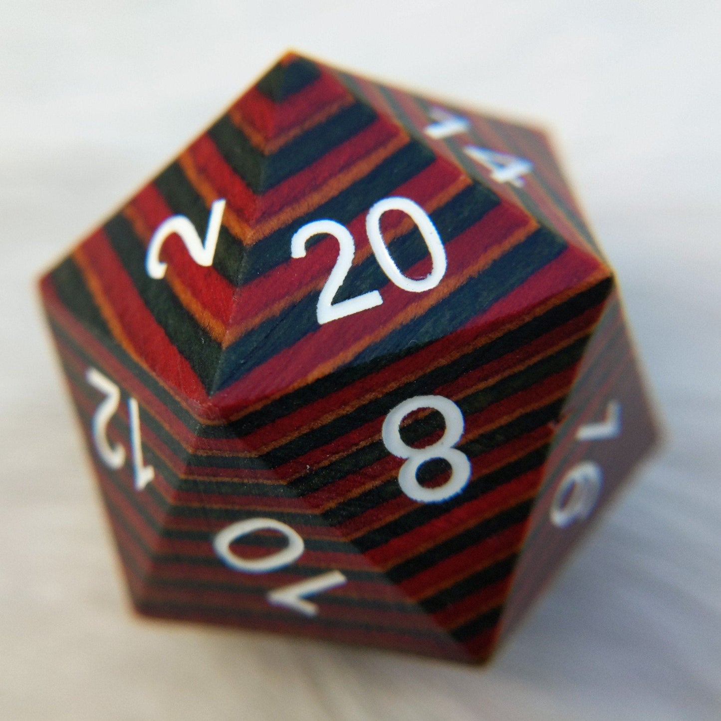 Large wood D20 with red, blue, and brown stripes displaying numbers, perfect for collectors or tabletop gaming enthusiasts.