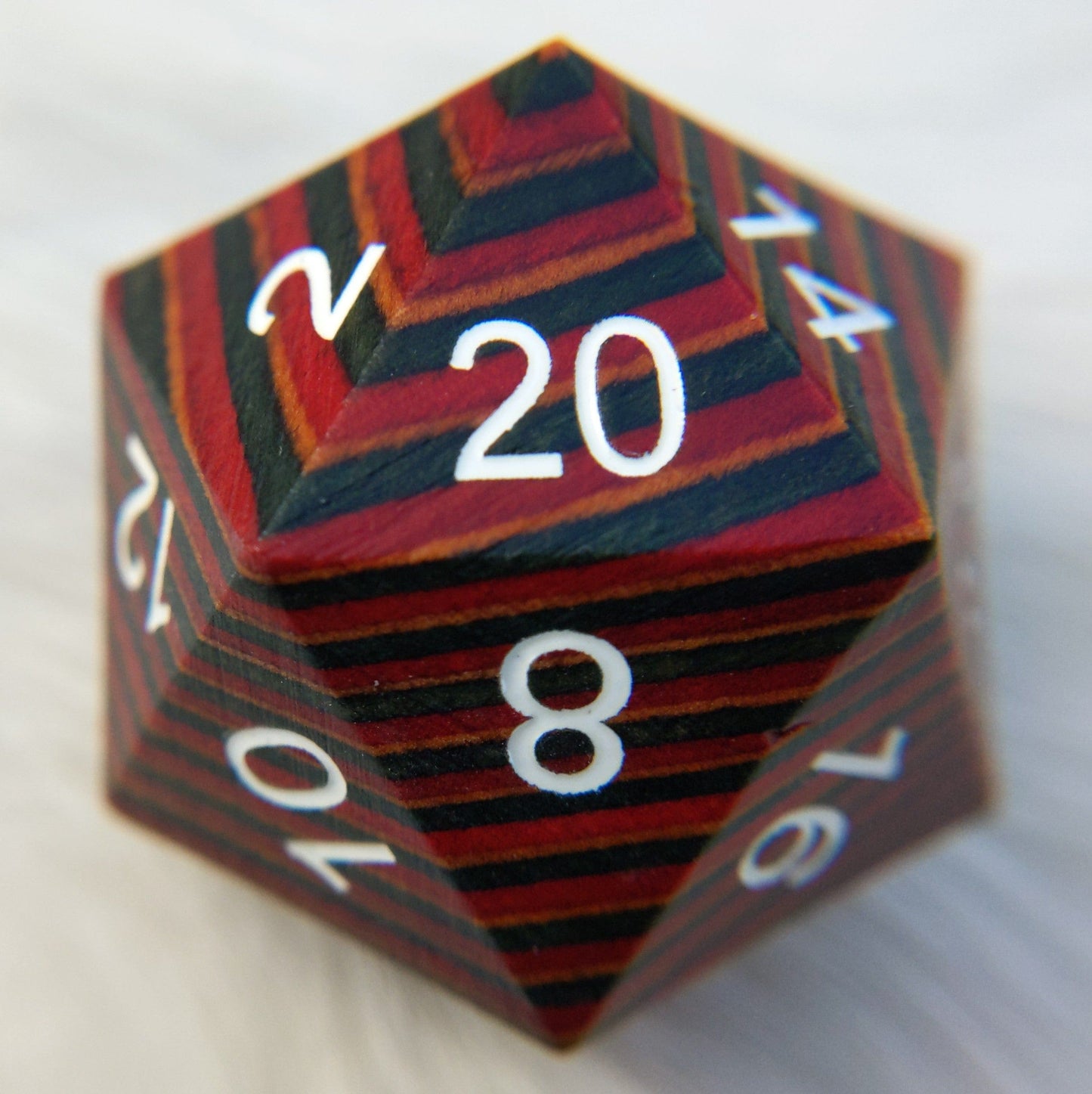 Large wood D20 dice with red, blue, and brown stripes, featuring white numbers including a prominent 20, gift or collection piece.