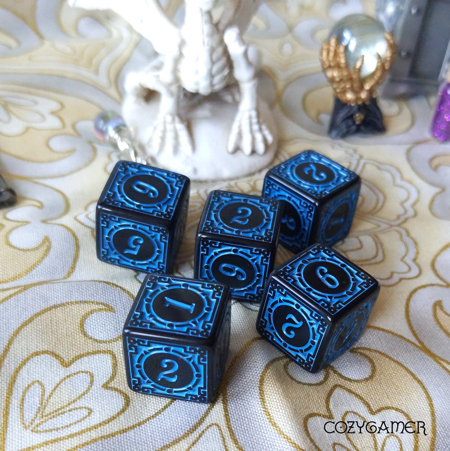 Black and blue set of 5 six-sided dice with intricate design on a decorative surface, perfect for tabletop gaming enthusiasts.