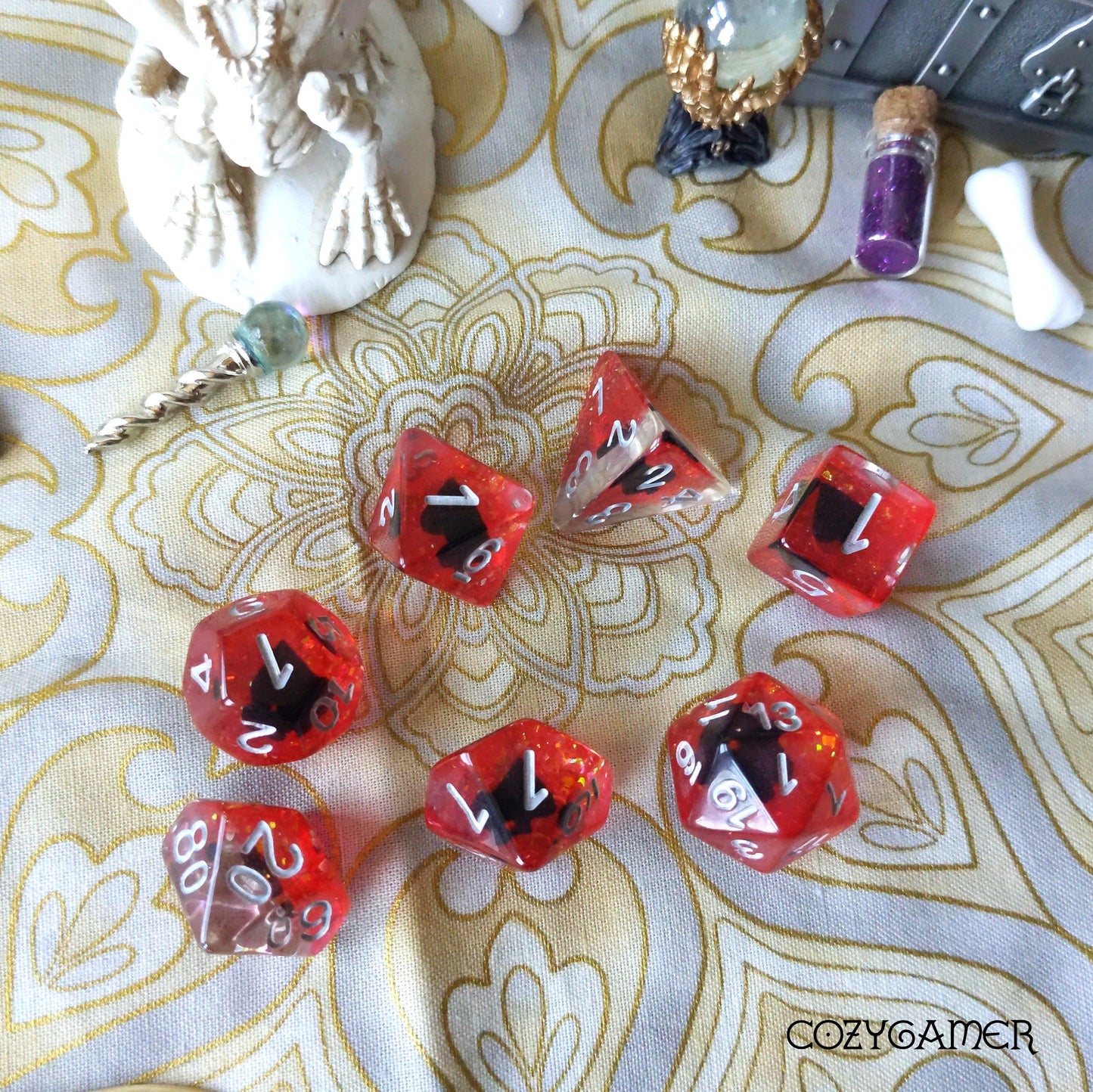 Red card suit themed polyhedral dice set for Dungeons and Dragons on a patterned background with gaming accessories.