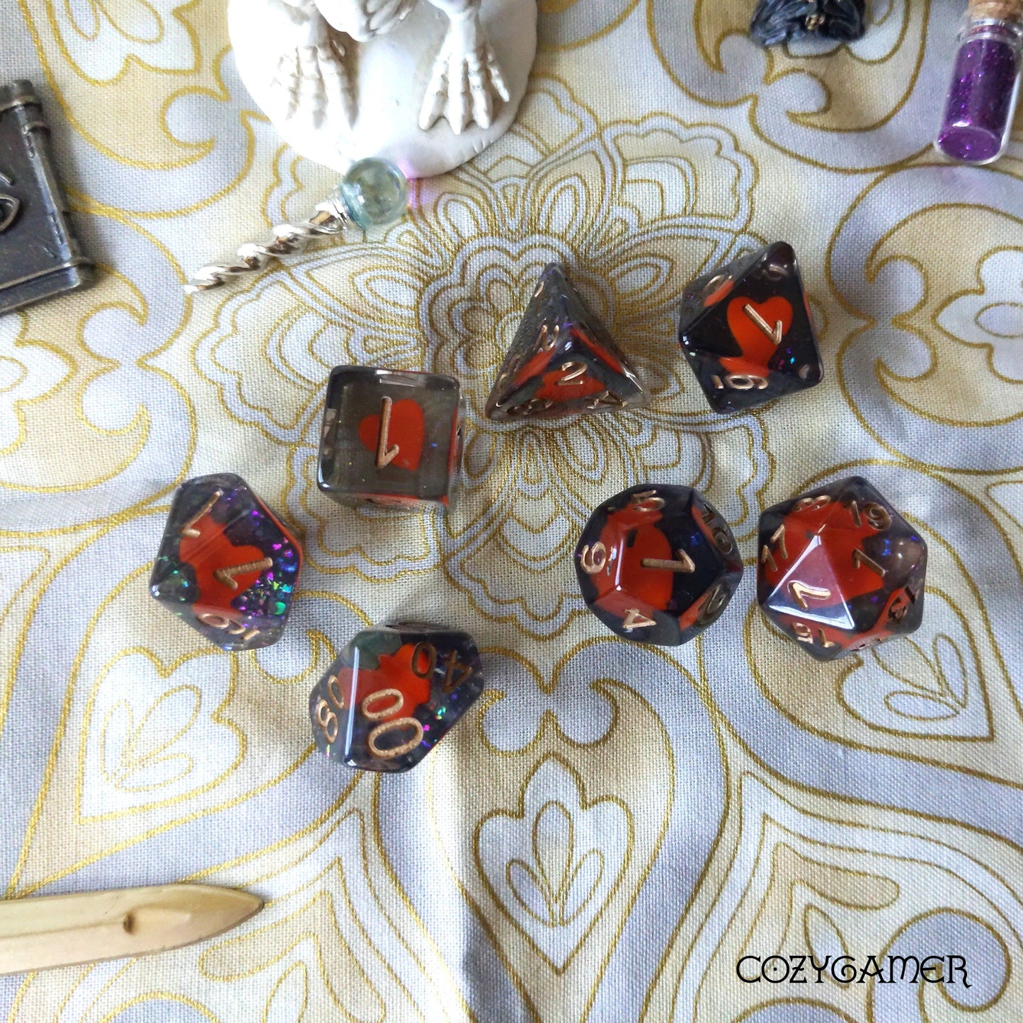 Shape of My Heart polyhedral dice set with card suit theme displayed on decorative cloth background for tabletop RPGs.