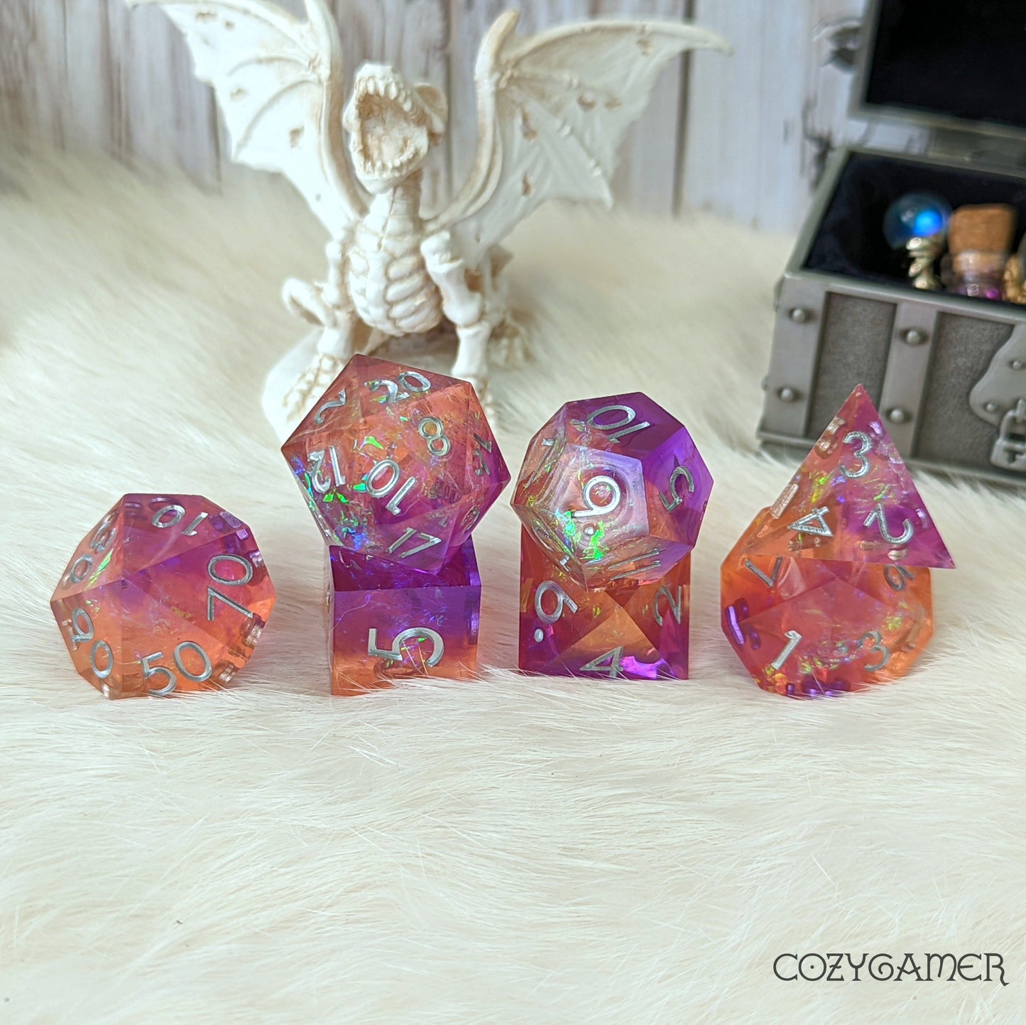 Purple and orange sharp edge dice set with glitter, ideal for DnD, role-playing games, or Magic the Gathering, shown with dragon figurine.
