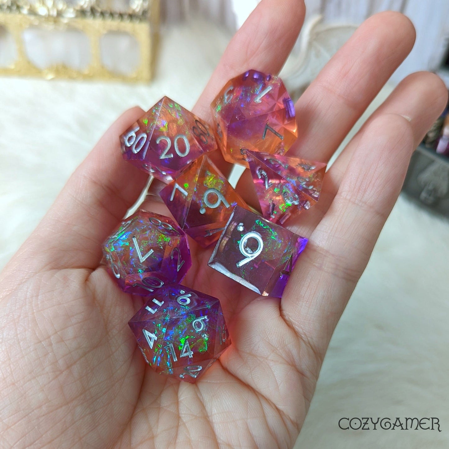 Hand holding a 7-piece set of sharp edge DnD dice in purple and orange with glitter, perfect for tabletop games and Magic the Gathering.