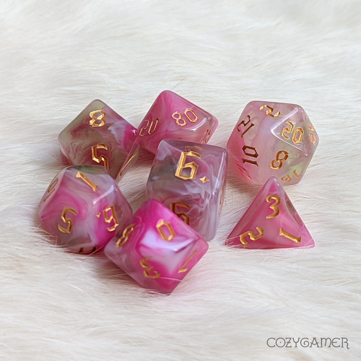 Superbloom marbled pink, white, and green polyhedral dice set for tabletop RPGs, with gold numbering on fluffy background.