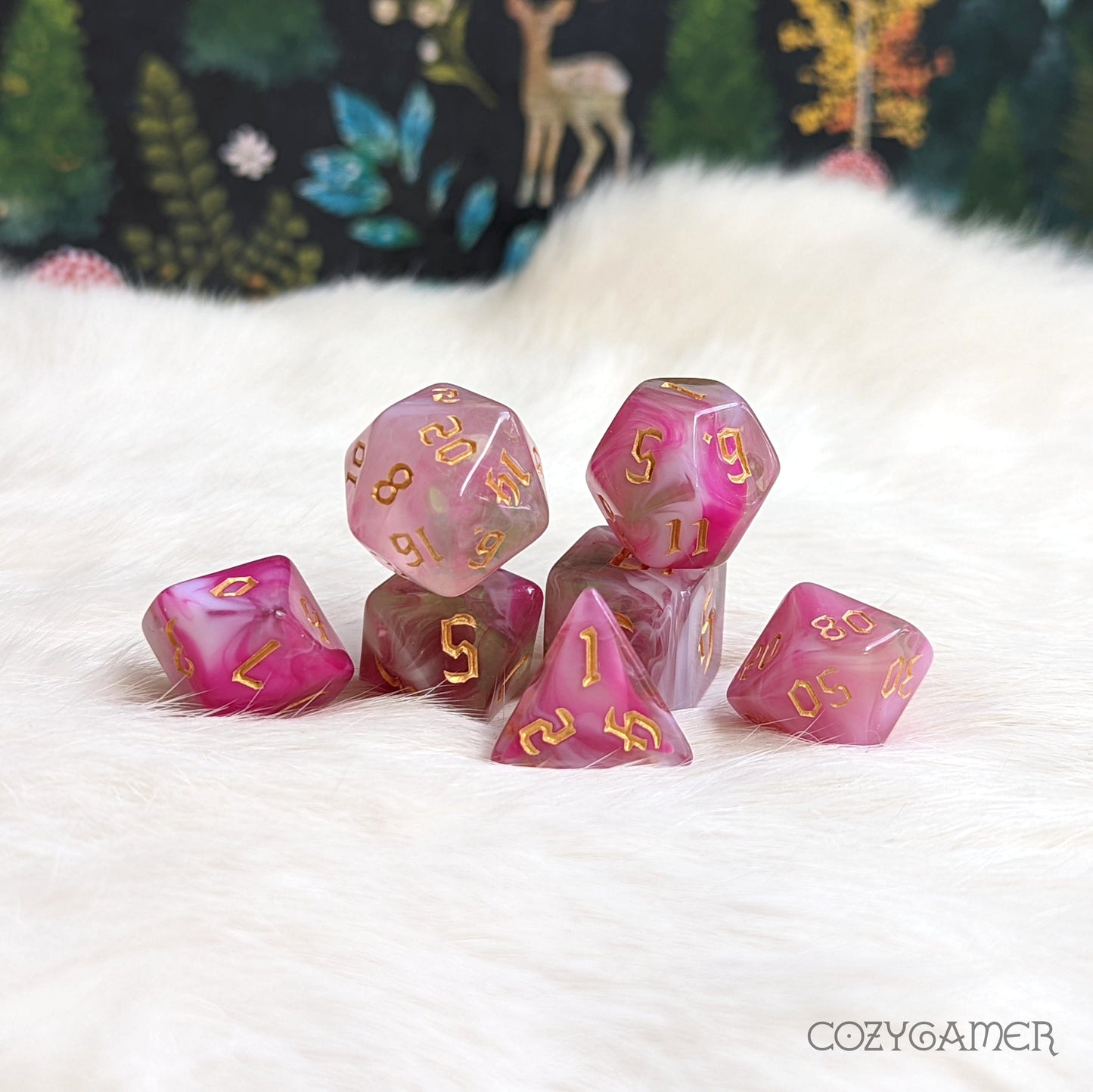 Marbled pink polyhedral dice set for tabletop games on white fur background with nature-themed decor.