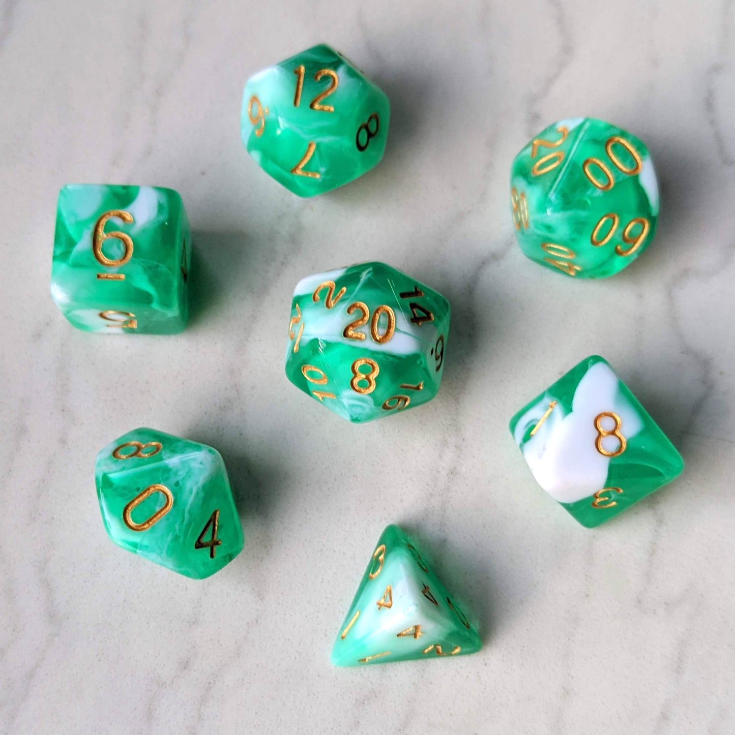 Teal and white marbled dice set with gold numbers for tabletop RPGs like Dungeons and Dragons, featuring a 7-piece collection.