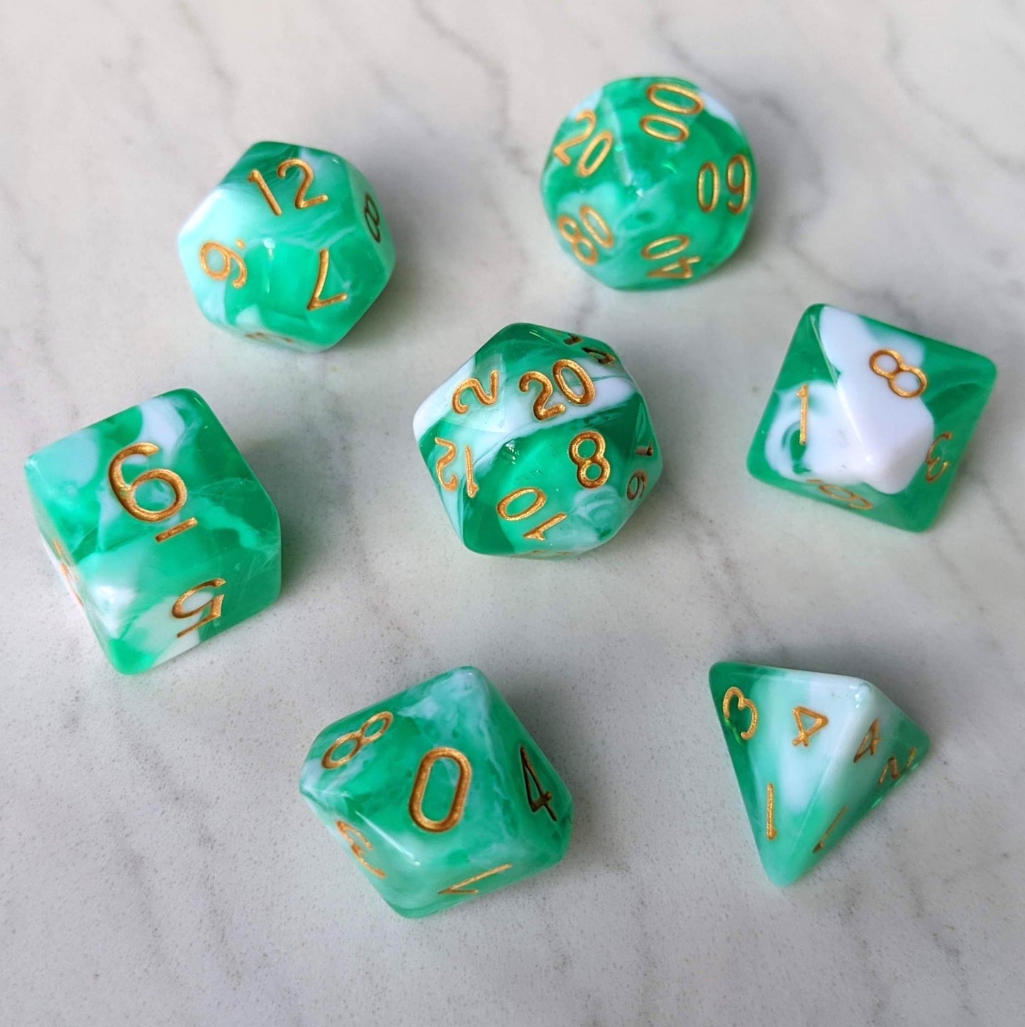 Teal and white marbled 7-piece dice set with gold numbers for tabletop RPGs like Dungeons and Dragons on a marble surface