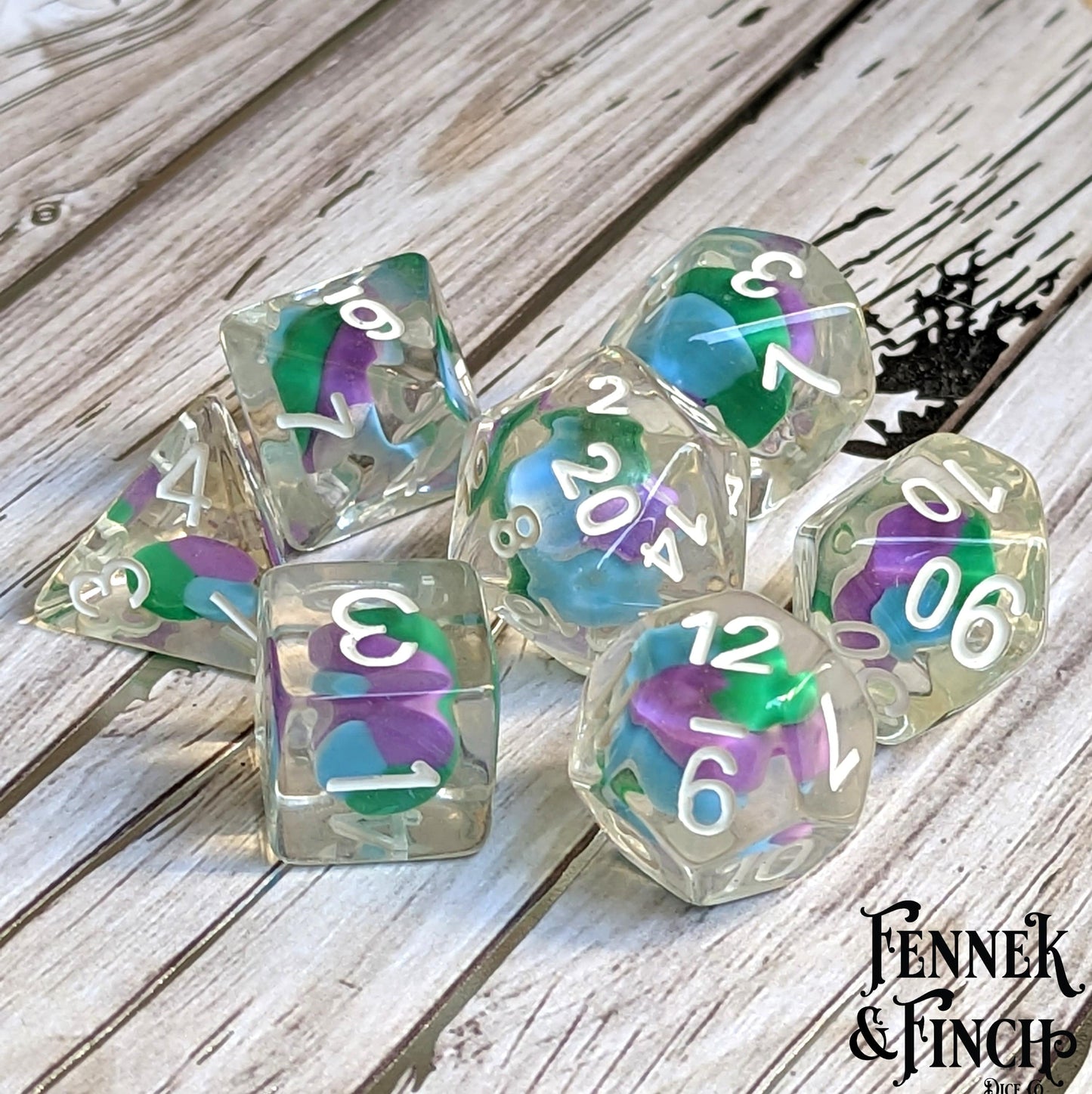 Unicorn Candy Swirl Dice Set with colorful clay swirl centers for DnD and TTRPG, featuring 7 polyhedral dice on a wooden table.