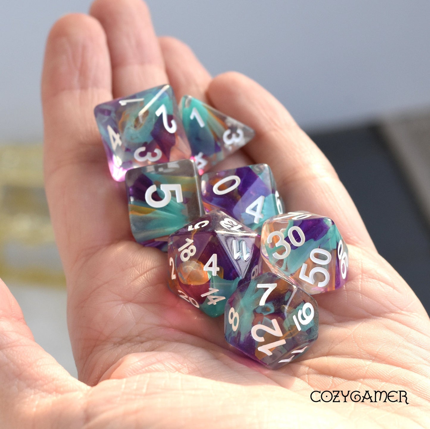 Colorful Unknown Lands Dice Set in hand, translucent polyhedral dice perfect for Dungeons and Dragons tabletop games.