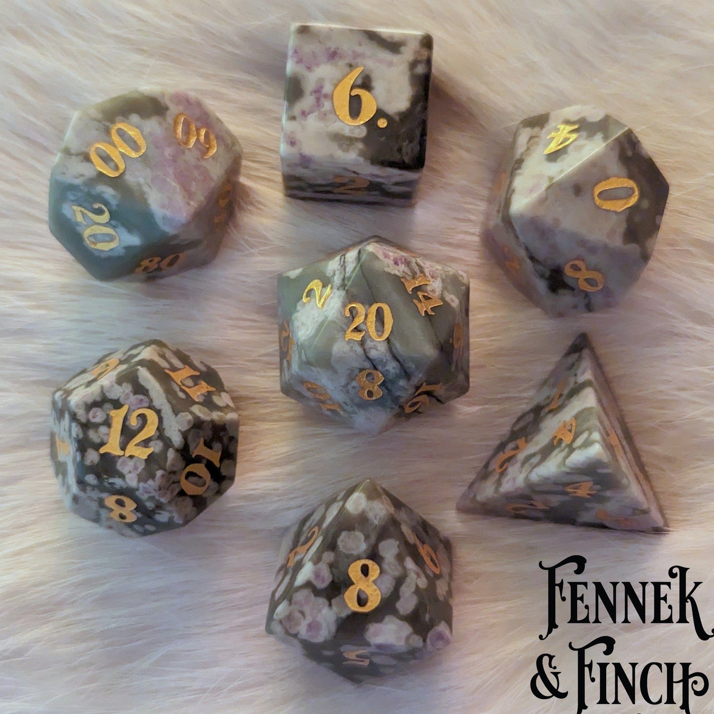 White and Green Jasper Dice Set, 7 Piece TTRPG Real Gemstone Dice, displayed in a circle on a soft surface, featuring carved numbers.