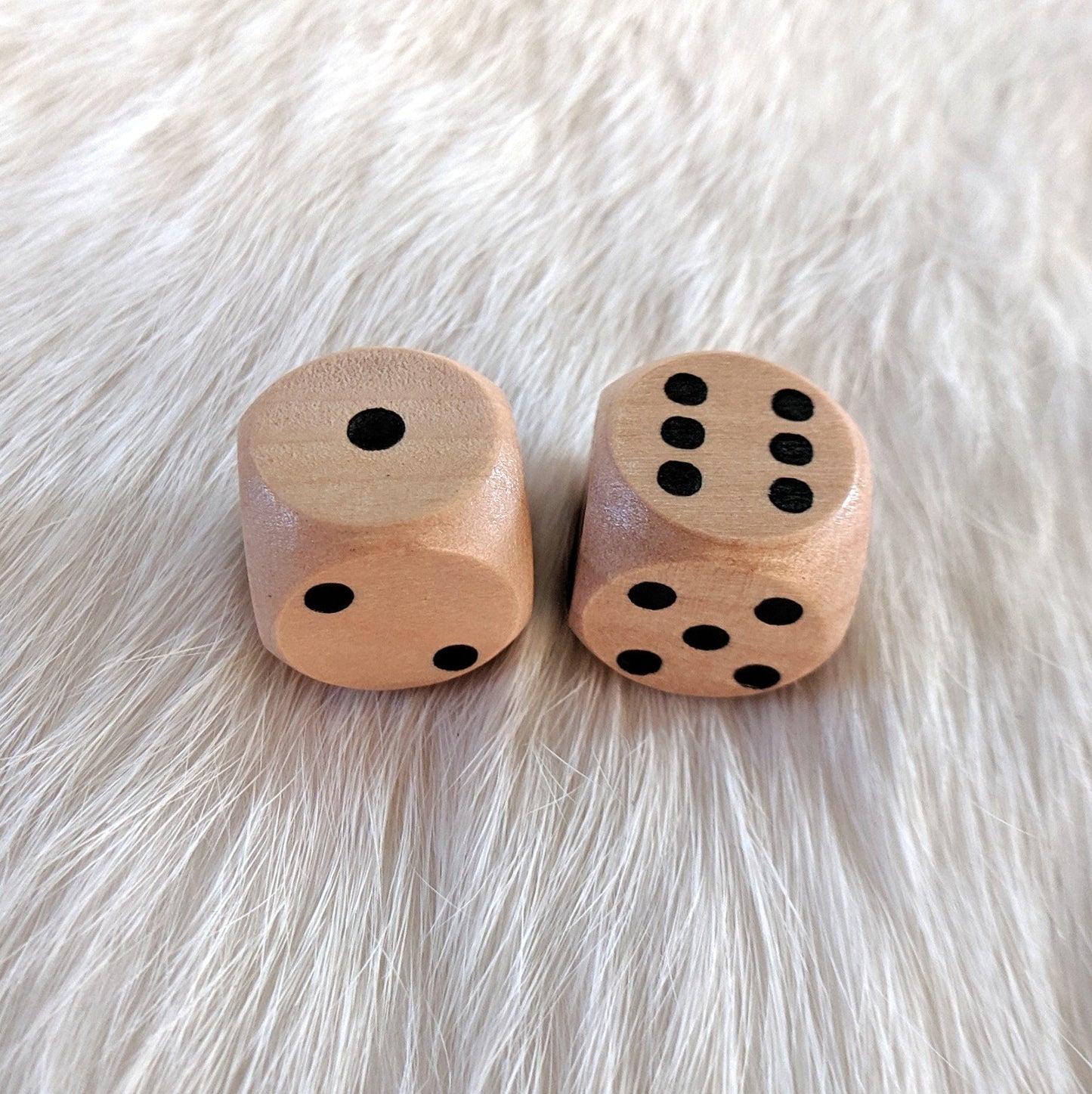 Light wooden D6 dice set on a soft fur background, perfect for gifts or collections.