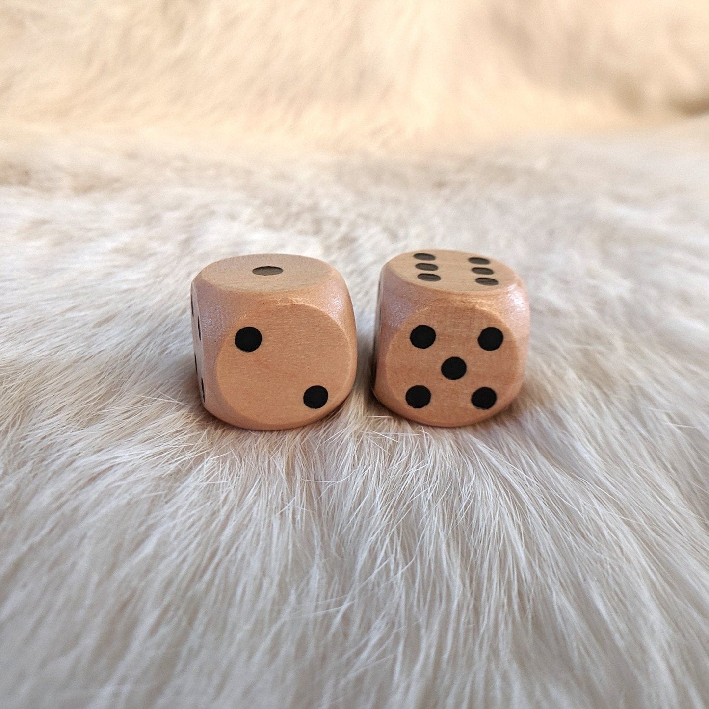 Two light wooden D6 dice on furry surface, perfect for gifts or collections.