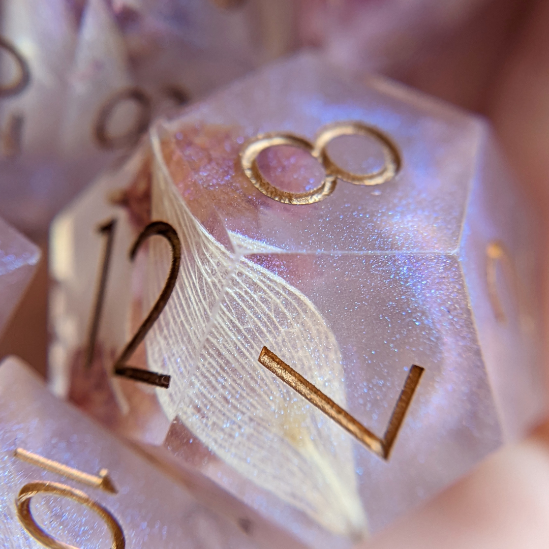 Close-up of handcrafted sharp edge dice with intricate floral designs, perfect for DnD gameplay and collectors at Fennek and Finch.