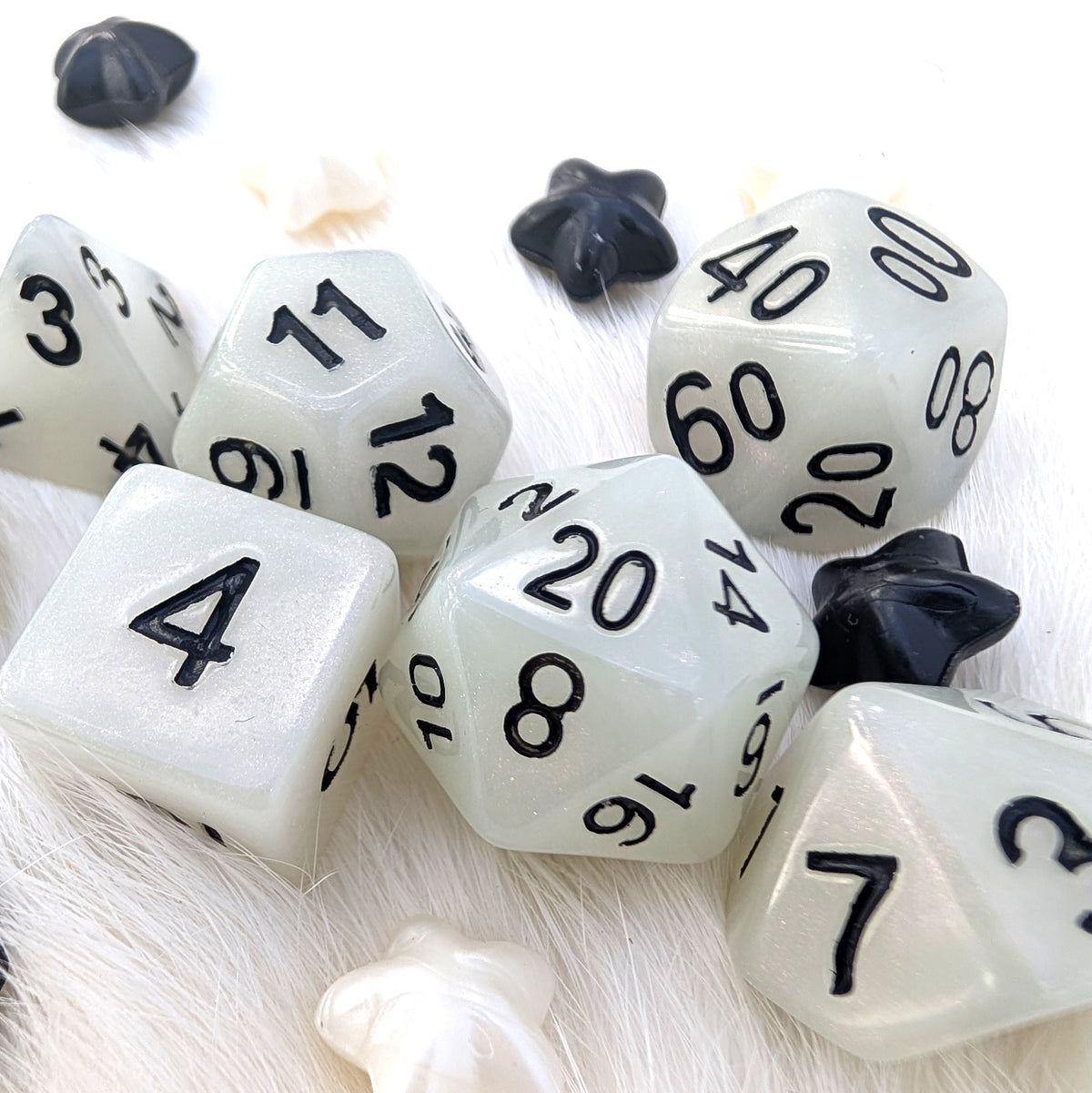 Ghostlight 7-piece white resin DnD dice set with opaque pearlescent shimmer that catches the light and contrasting black numbering