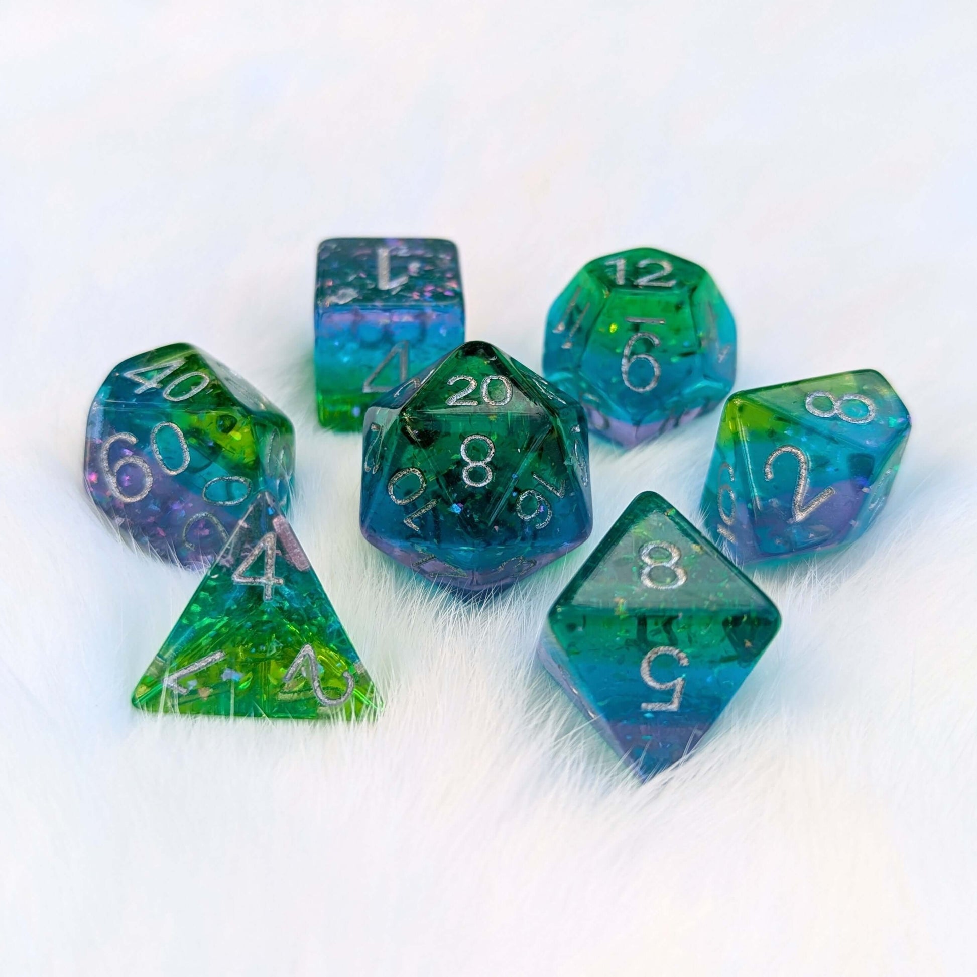 Aurora Sparkle Dice Set with green, blue, and purple hues and glitter on a white background, perfect for tabletop games.