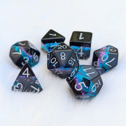 Midnight Nebula Dice Set with black and glittery blue-purple layers on a fluffy white surface.