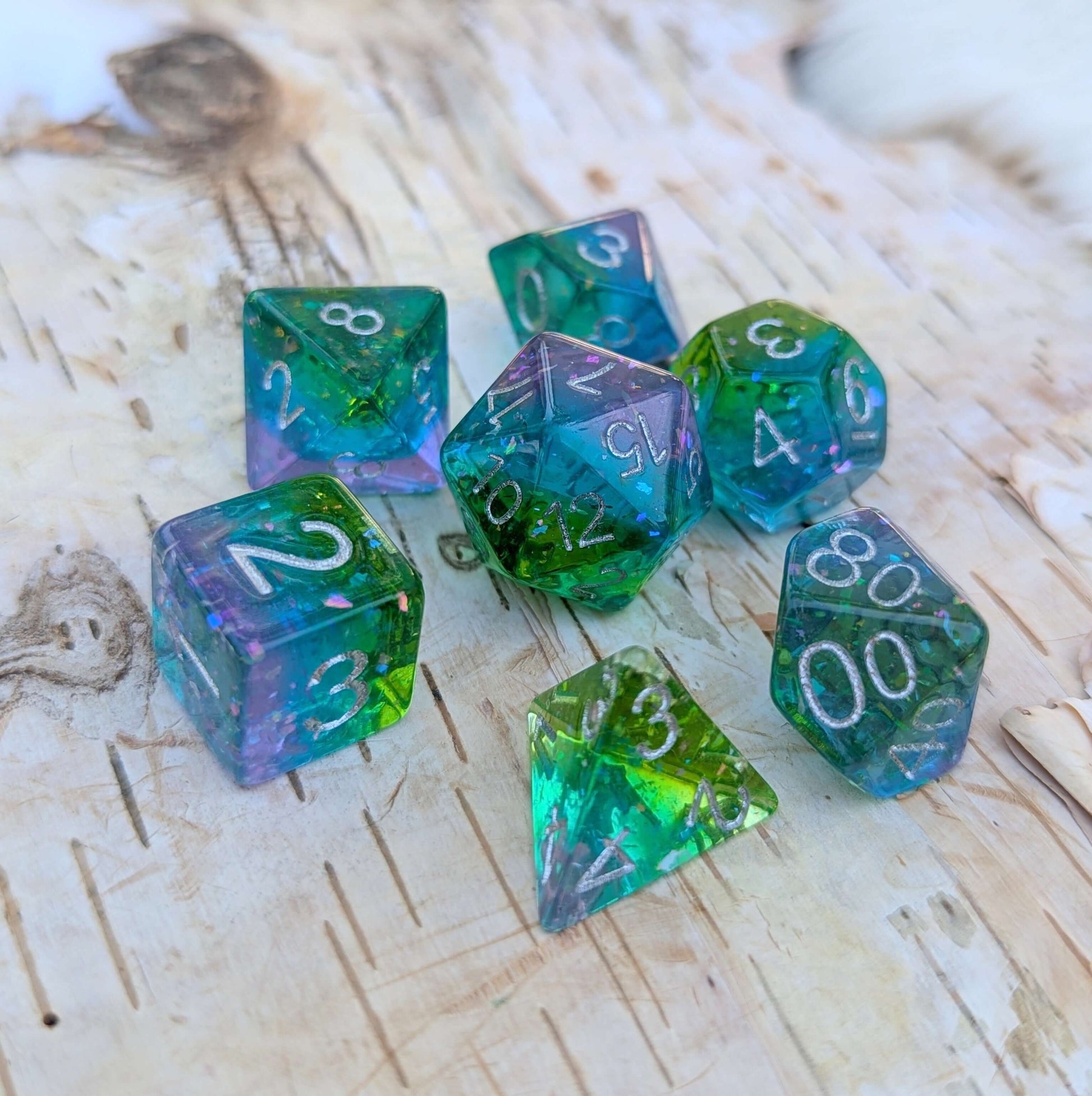 Aurora Sparkle Dice Set with iridescent glitter in green, blue, and purple, inspired by the northern lights on a wooden surface.