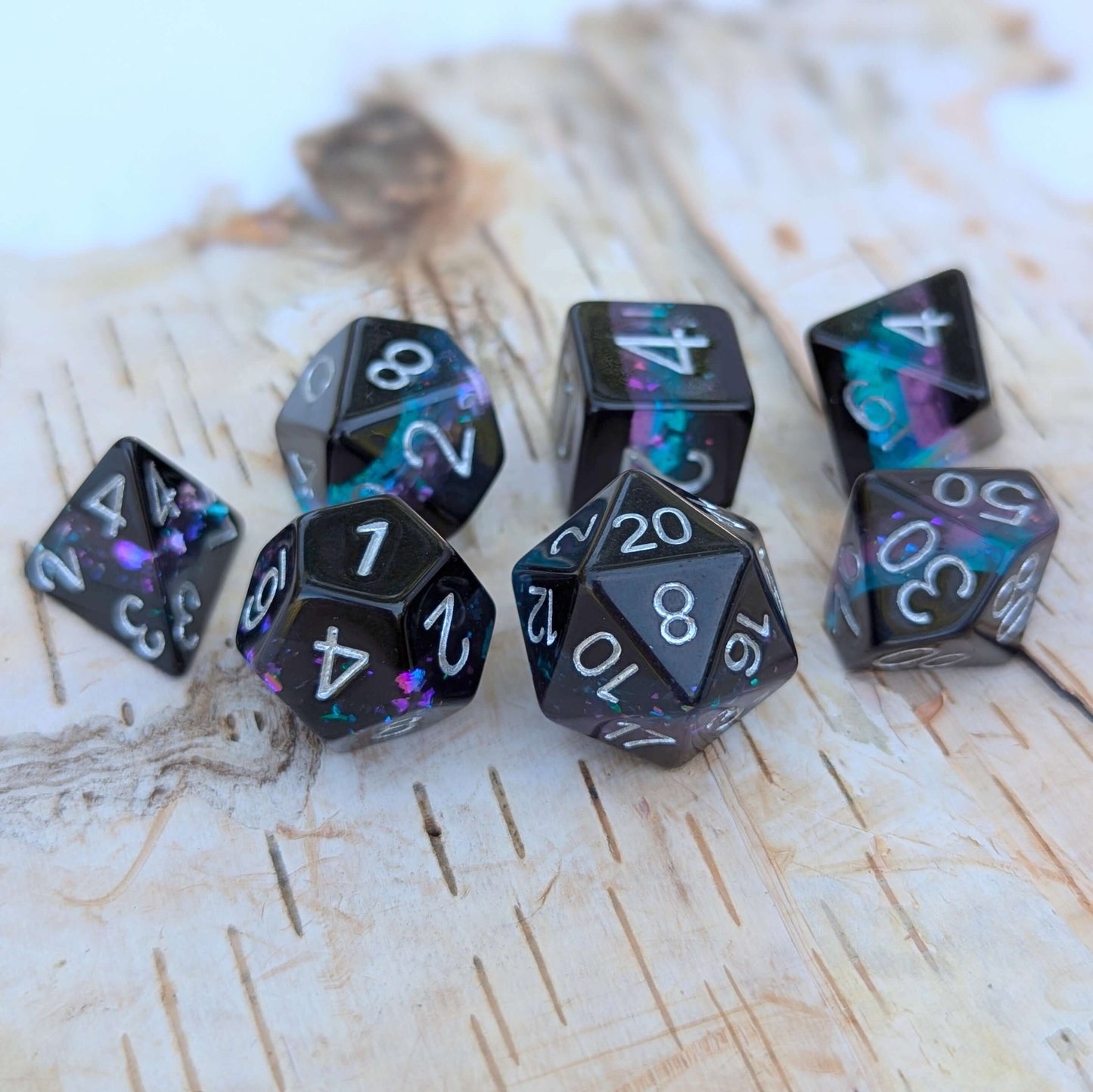 Midnight Nebula dice set on wooden background, featuring round-edge dice with black, blue, and purple glittery layers.