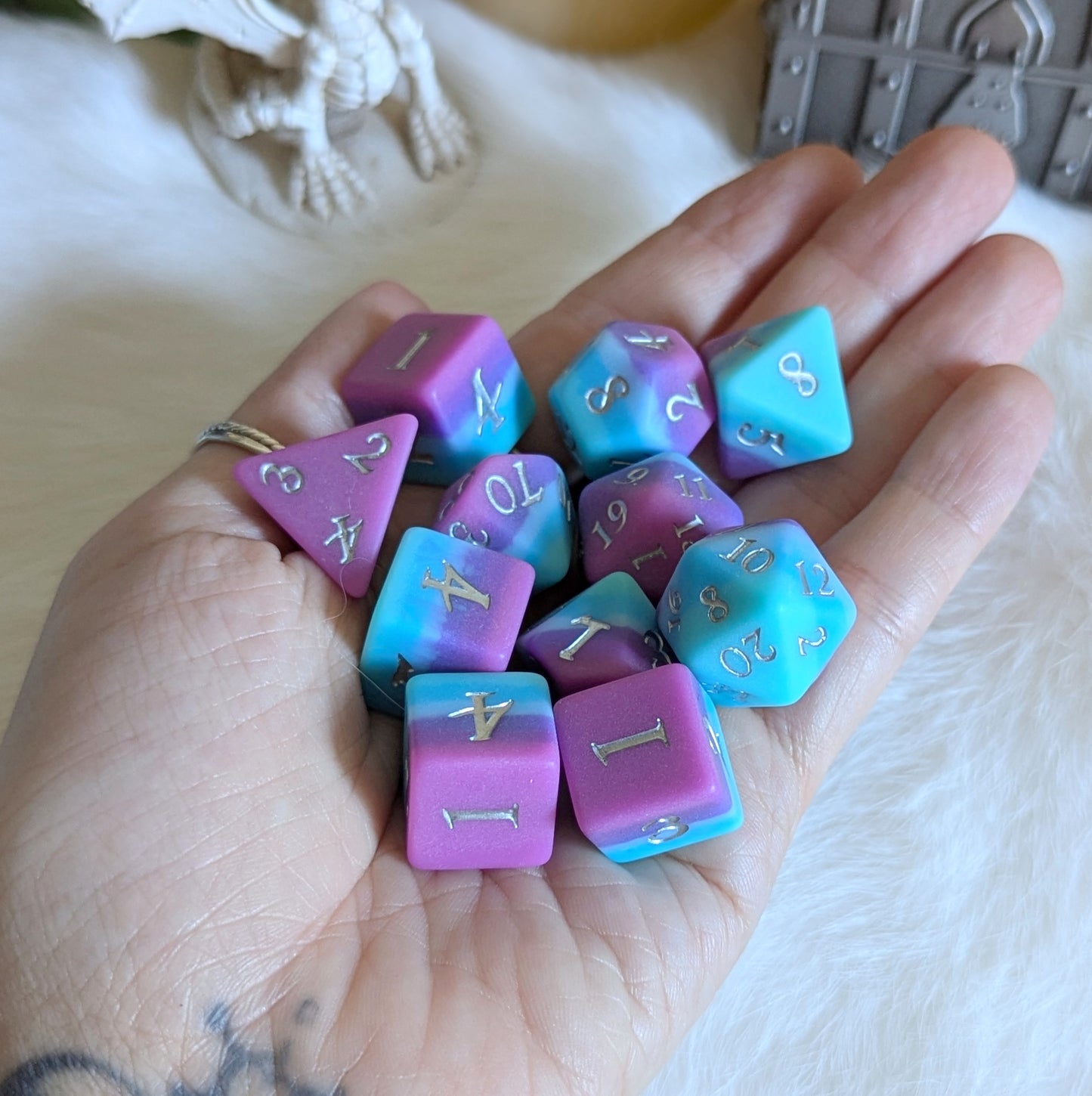 Hand holding Twilight Serenity Dice Set, featuring ombre shades of teal, blue, and purple with a matte finish, for tabletop gaming.