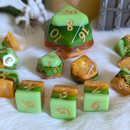 Timberlight dice set with green and earthy tones, featuring gold fantasy numbers, displayed on a fluffy white surface.