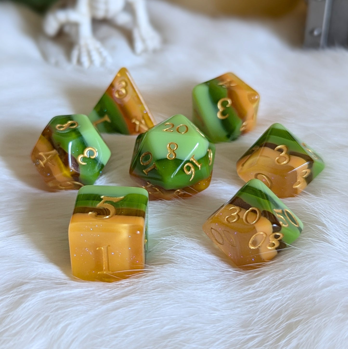 Timberlight Dice Set with gradient hues of green, brown, and gold numbers, displayed on a white fur surface.