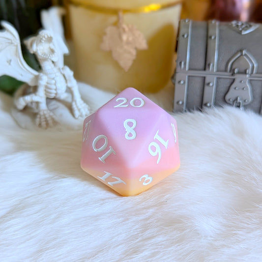 Sorbet Sunset Large D20 die with pink to yellow ombre finish and white numbers on faux fur, surrounded by fantasy decor.