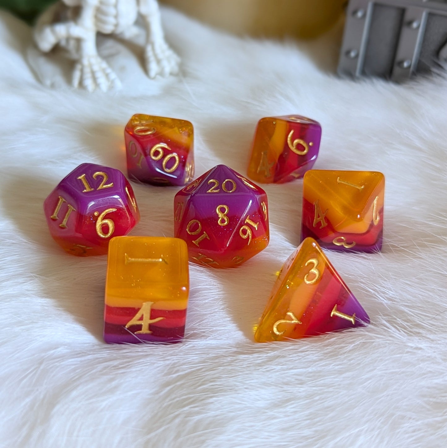 Emberstorm Dice Set with vibrant purple, red, and orange ombre layers, featuring golden numbers and a shimmering finish.