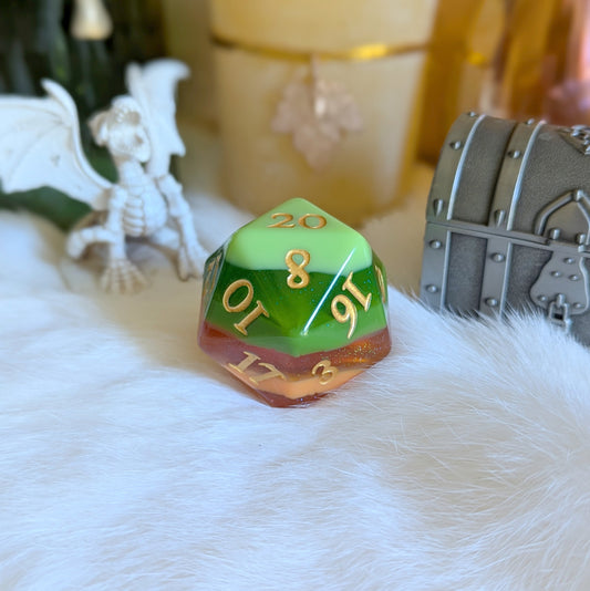 Colorful green and orange D20 die with gold numbers on a white surface, surrounded by fantasy-themed figurines and decor.