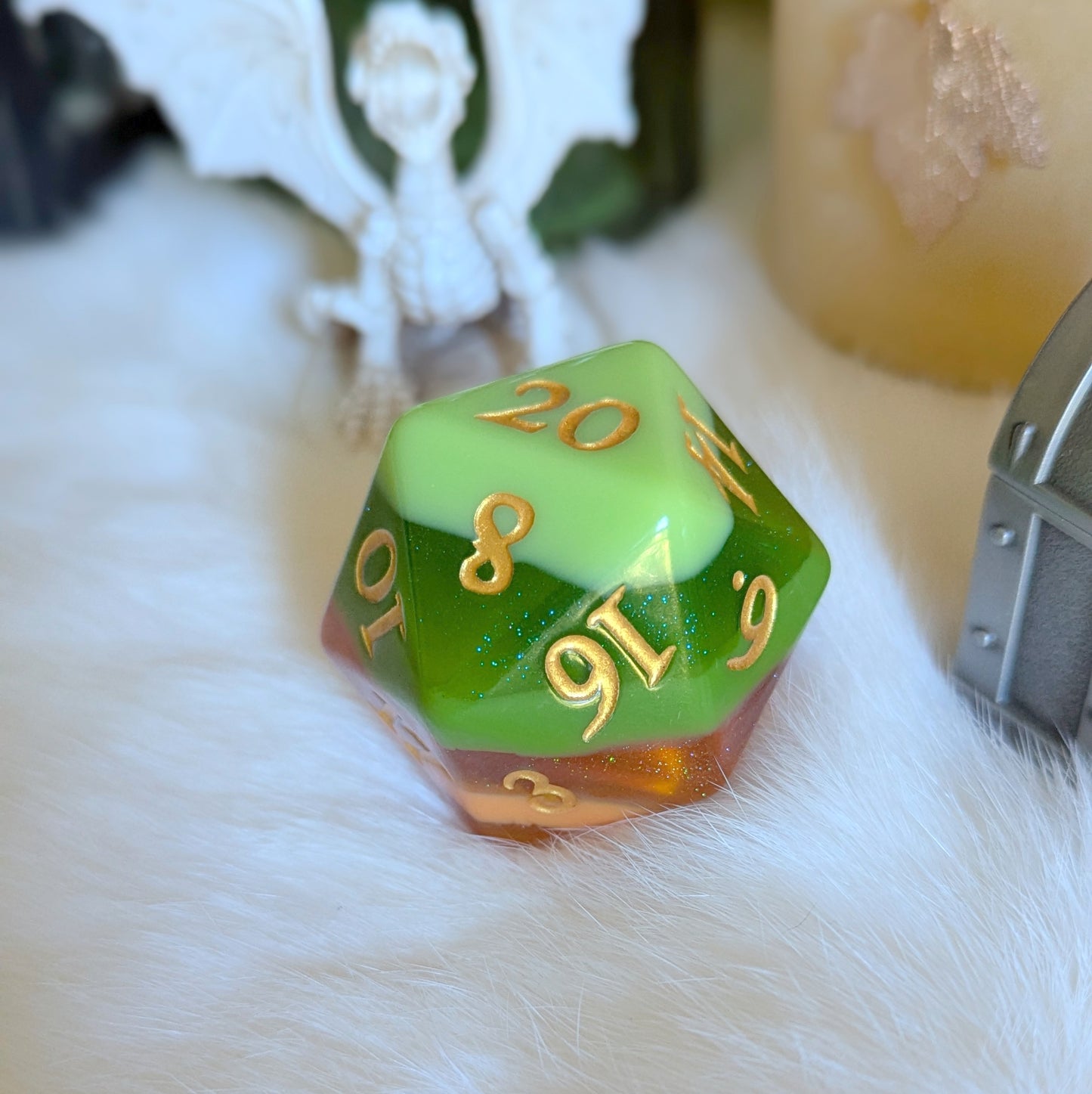 Multicolored D20 die with gradient green to orange tones and gold numbers on a white fur surface, surrounded by decor.