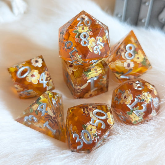 Honey Blossom sharp-edge dice set with bee and flower designs, in golden honey hue, displayed on a soft white surface.