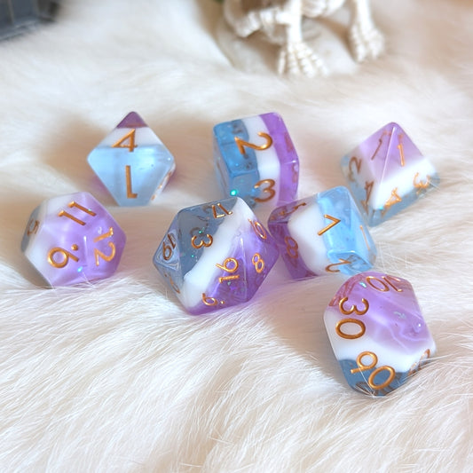 Mystic Tide Dice Set with round-edges, featuring clear blue, opaque white, and purple layers on a soft white background.