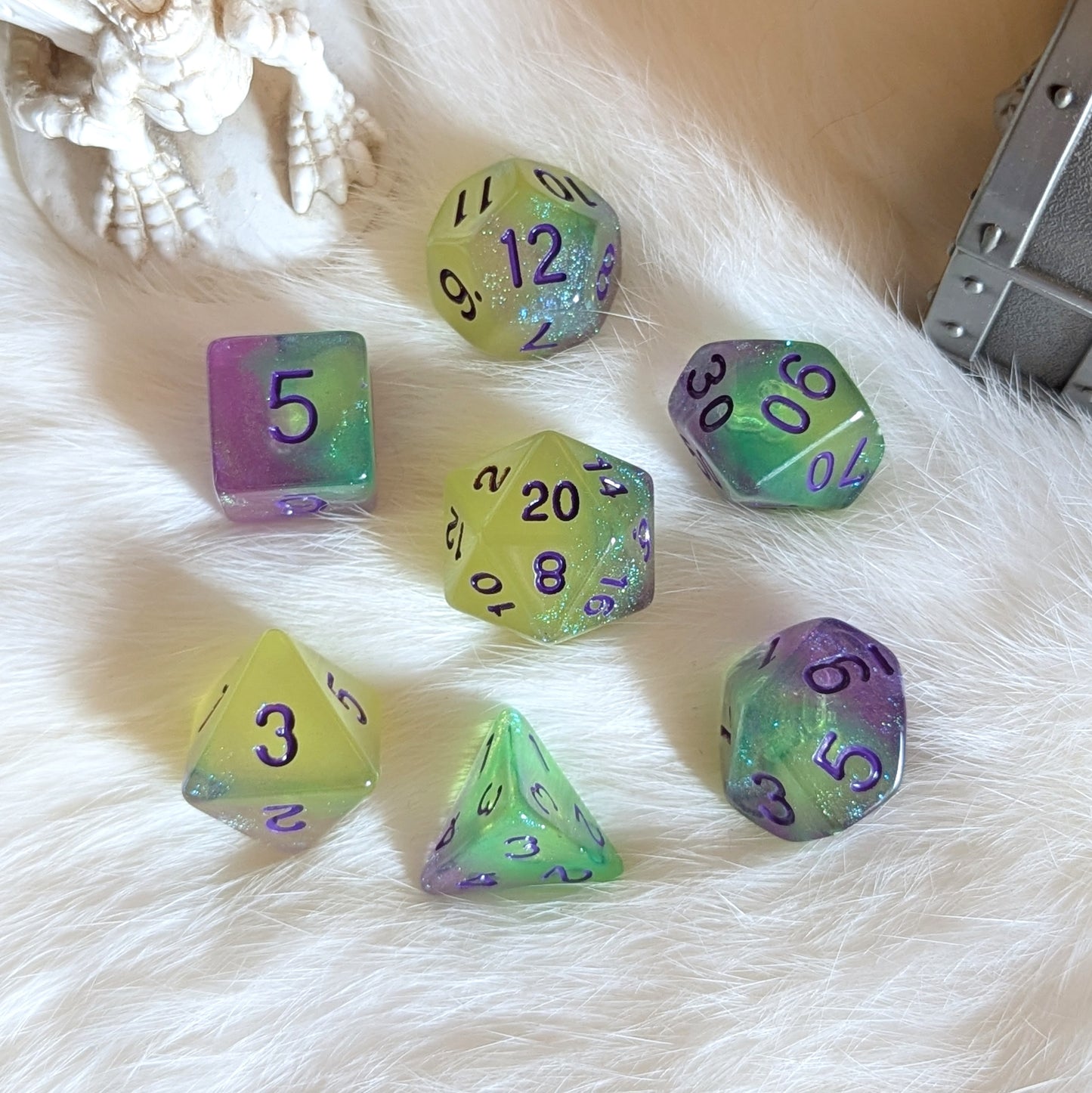 Dreamlight Grove glow-in-the-dark dice set with green-yellow, teal, and purple swirls, featuring purple numbers and rainbow glitter.