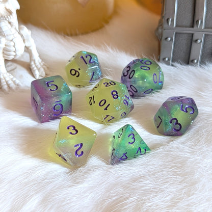 Dreamlight Grove glow-in-the-dark dice set with green-yellow, teal, and purple swirls and purple numbers on white fur.