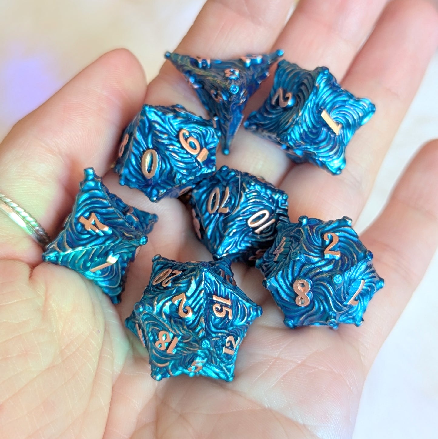 Blue Enchanted Bark Metal Dice Set with copper numbers displayed on a hand, featuring a bark-like texture and sky-inspired design.